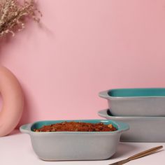 three bowls with food in them sitting on a table next to a vase and fork