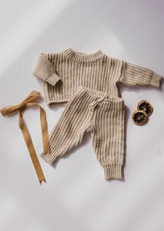 a baby's knitted outfit and tie laying on top of a white surface