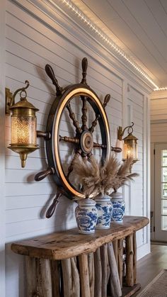 a wooden table topped with blue and white vases next to a wall mounted ship wheel