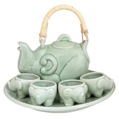 an elephant tea set on a tray with four cups and a basket in the middle