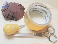 a pair of scissors and tape sitting on top of a wooden table next to some construction supplies