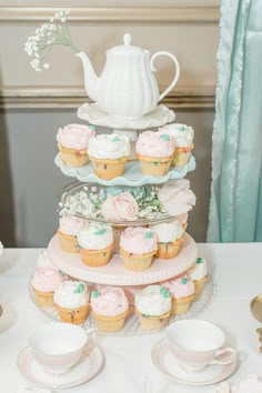 cupcakes are stacked on top of each other in front of a teapot