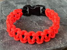 a red and black bracelet sitting on top of a rock