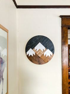 a wooden wall hanging on the side of a white wall next to a framed photo