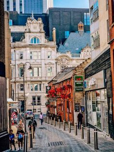 people are walking down the street in an old city with tall buildings on either side