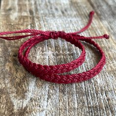 two red braided bracelets sitting on top of a wooden table