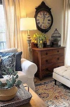 a living room filled with furniture and a large clock on the wall above it's windows