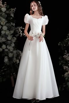 a woman in a white dress standing next to flowers