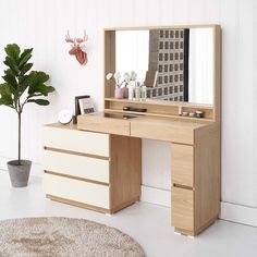 a wooden desk with a mirror on top of it and a potted plant next to it