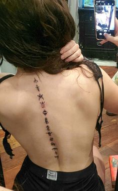 the back of a woman's neck with chinese writing on her lower back tattoo