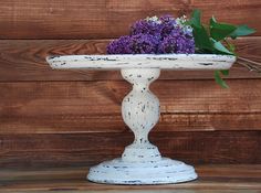 a white pedestal with purple flowers in it