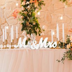 a table topped with candles and flowers next to a sign that says mr and mrs