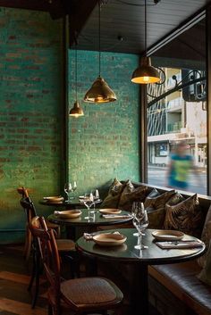 a restaurant with green brick walls and wooden tables set up for two people to eat