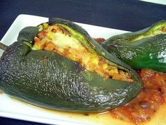 two stuffed peppers sitting on top of a white plate