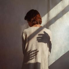 a woman standing in front of a wall with her hand on the back of her body