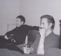 black and white photograph of two men sitting on a couch, one with a candle in his hand