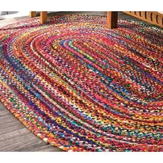 a multicolored area rug on a wooden floor with a bench in the background