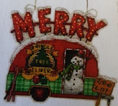 a cross stitch christmas ornament with a snowman on the front and words merry