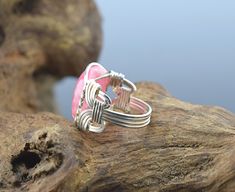 "Rhodochrosite Sterling Silver Wire Wrapped Ring This style ring is often called a Pharaoh's ring due to the same style being found in the pyramids of Egypt. This ring is entirely handcrafted with sterling silver wire. The ring has an 18 x 13 mm Rhodochrosite cabochon. There are variations in these stones! Some have more striations than others. Once made, these rings can not be re-sized. Band Wrapping - If you would like the band of your ring wrapped like the last picture, please the wrapped ban Handmade Pink Promise Ring, Pink Bohemian Rings For Jewelry Making, Nickel Free Pink Promise Ring, Pink Open Ring, Handmade Adjustable Ruby Ring, Unique Pink Open Ring, Handmade Pink Sterling Silver Rings, Handmade Unique Pink Ruby Ring, Unique Handmade Pink Ruby Ring