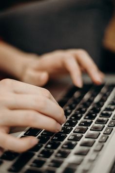 a person typing on a laptop computer with their hands resting on the keyboard and one hand touching the screen