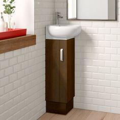 a white sink sitting next to a wooden cabinet in a bathroom under a mirror on the wall