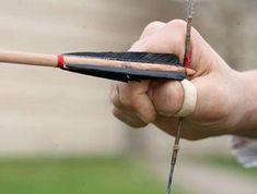 a hand holding a wooden bow and arrow