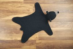 a black bear shaped rug sitting on top of a wooden floor