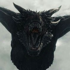 a close up of a dragon head with clouds in the background