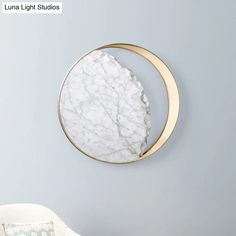 a white chair sitting in front of a wall mounted marble circle with a gold frame