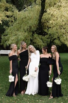 four bridesmaids in black dresses posing for the camera