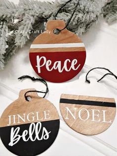 three wooden ornaments with the words peace, jingle bells and noel on them hanging from a christmas tree