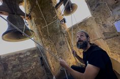 a man sitting on the ground with two bells hanging from it's ceiling and looking up