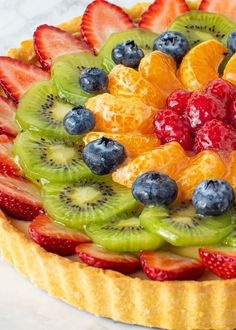 a fruit tart topped with sliced kiwis, strawberries and blueberries