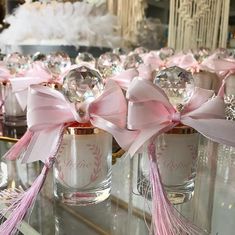 several small glass jars with pink bows on them