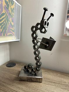 a metal sculpture sitting on top of a wooden table next to a framed art piece