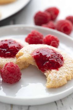 raspberry cheesecakes on a white plate with fresh raspberries