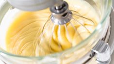 a food processor filled with yellow liquid and whisk