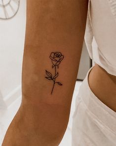 a woman's arm with a single rose tattoo on the left side of her arm