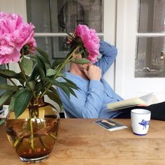 a person sitting at a table with flowers in a vase and books on the table