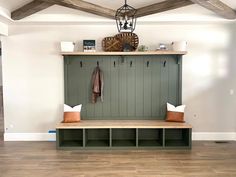 a wooden bench sitting in the middle of a living room next to a wall mounted coat rack