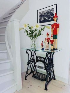 a vase with flowers on top of a table next to a sewing machine and toy soldiers