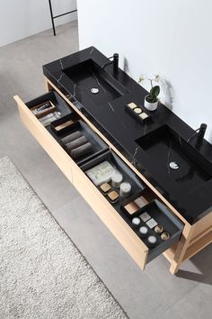 a bathroom vanity with black counter top and white rugs on the floor next to it