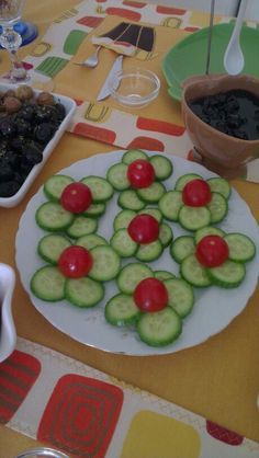 cucumbers and cherry tomatoes are arranged on a plate with olives in the middle