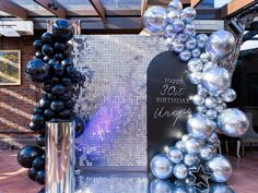 balloons are on display in front of a birthday sign and vases with black and silver balls