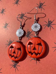 These Halloween earrings have a big orange pumpkin dangling from a creepy spiderweb charm! Spooky Red Halloween Jewelry, Novelty Orange Earrings For Halloween, Spooky Handmade Earrings For Halloween, Handmade Spooky Halloween Earrings, Spooky Handmade Halloween Earrings, Red Pierced Halloween Earrings, Red Pierced Earrings For Halloween, Spooky Pierced Earrings For Halloween, Dangle Halloween Earrings