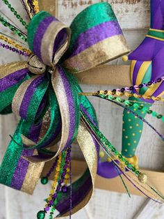 a purple, green and gold bow hanging from a door