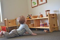 a baby laying on the floor in front of a book shelf