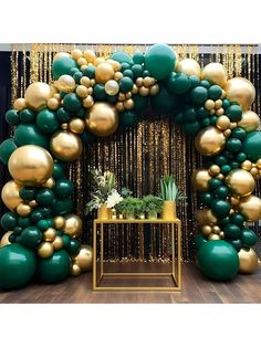 a green and gold balloon arch with balloons