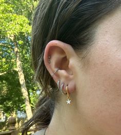 a close up of a person's ear with two rings on it and trees in the background