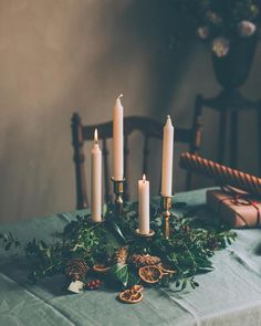 a table topped with candles and greenery on top of a blue cloth covered table